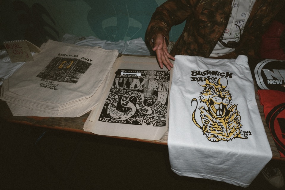 Bushwick Daily tote bags and a T-shirt on the merch table