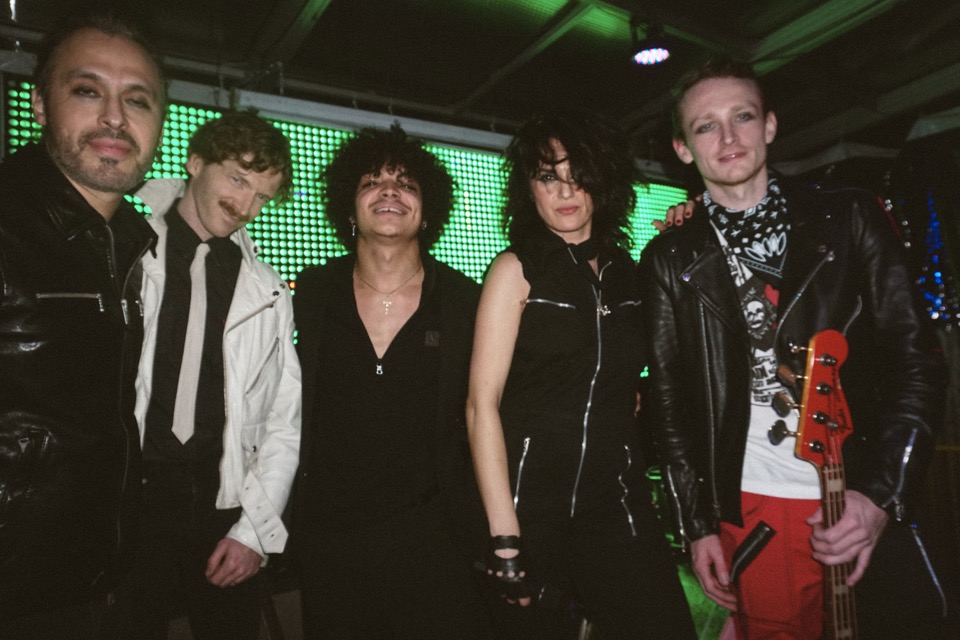 Five members of New Rock City posed in front of the stage